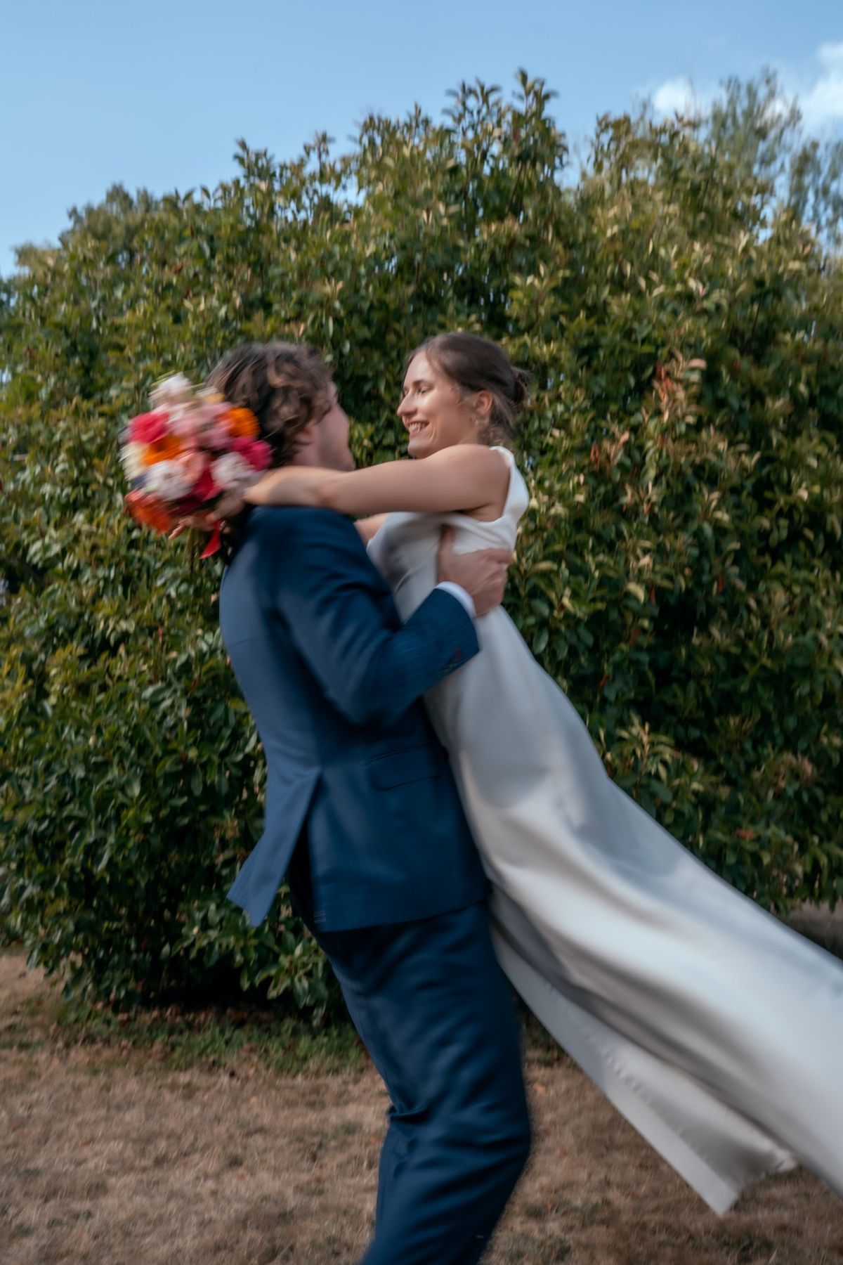 Le marié soulève la mariée, flou de mouvement et robe qui s'envole